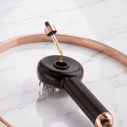 A close-up of a black and rose gold hair styling brush with a dropper bottle of oil being dispensed into its top opening, set against a white marble background with a rose gold tray.